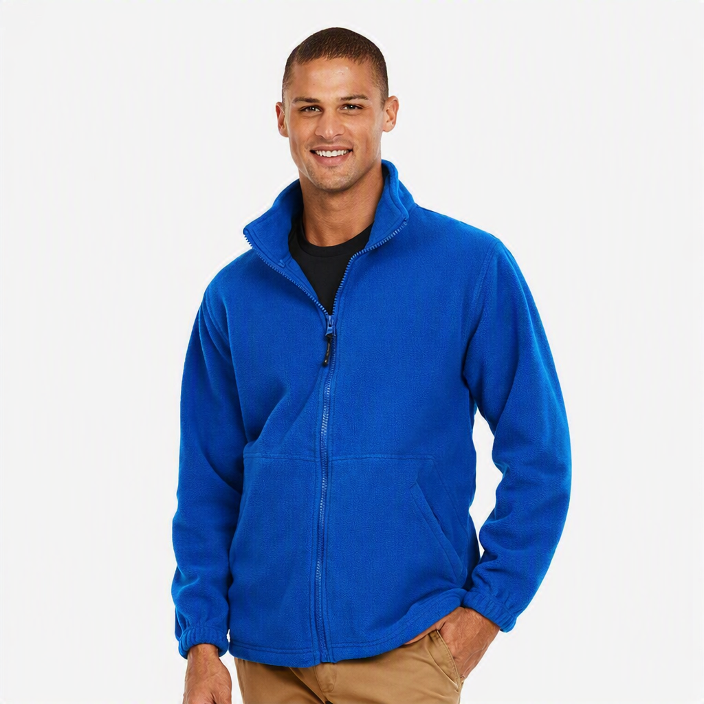 A man wearing a bright royal blue full-zip fleece jacket over a black t-shirt and khaki pants, standing against a light gray studio background.