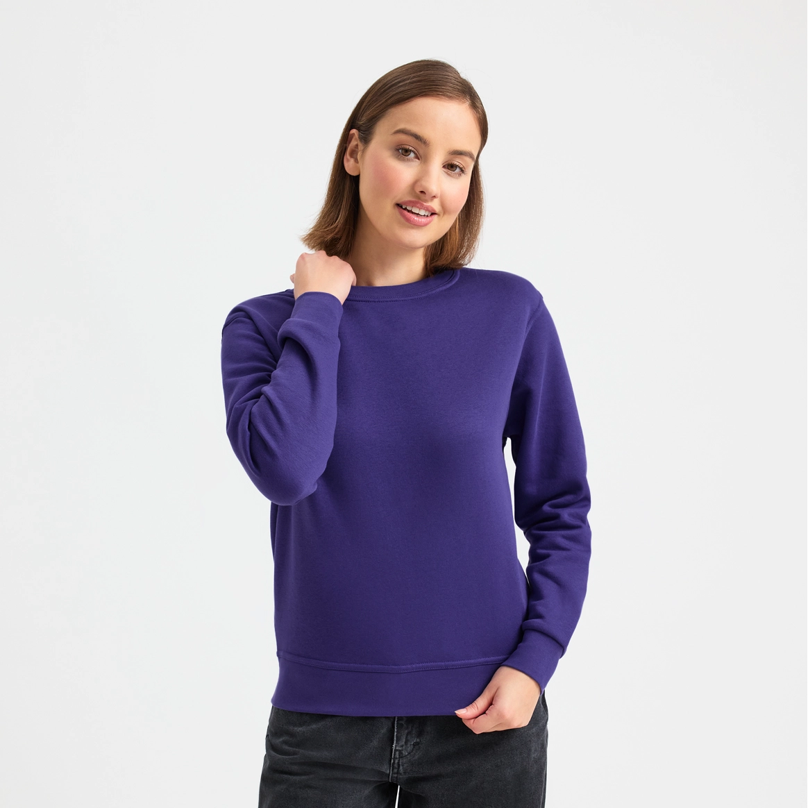 Woman wearing a purple sweater and black pants on a white background