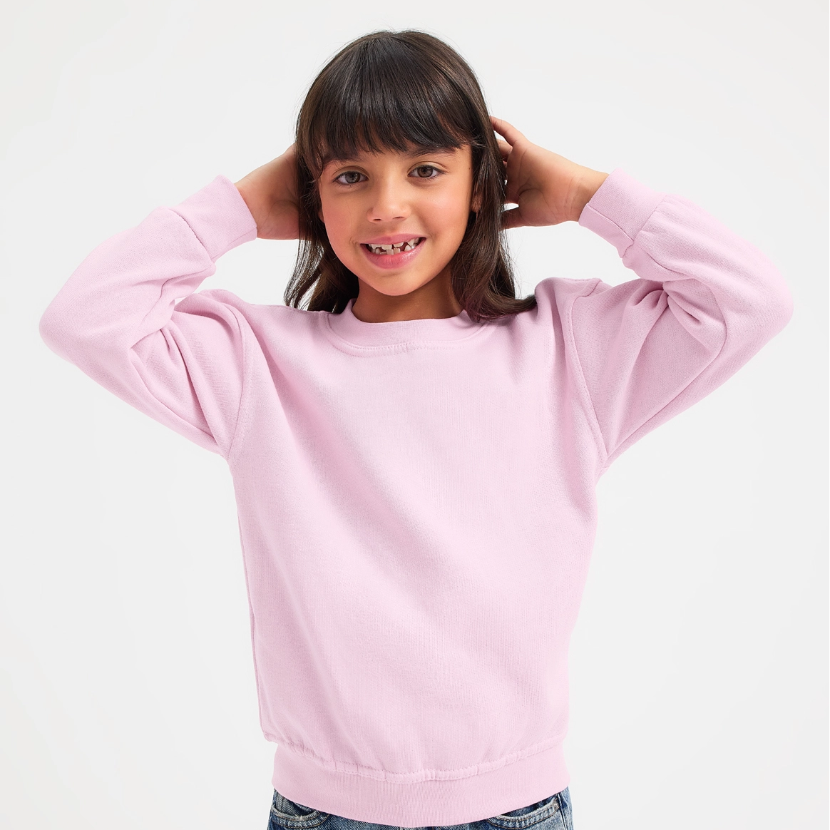 Child wearing a pink sweatshirt with white cuffs on a light gray background